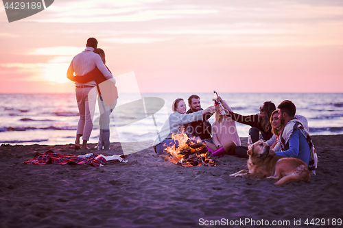 Image of Couple enjoying with friends at sunset on the beach