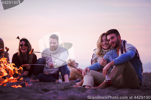 Image of Group Of Young Friends Sitting By The Fire at beach