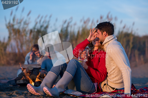 Image of Couple enjoying with friends at sunset on the beach