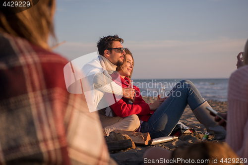 Image of Couple enjoying with friends at sunset on the beach