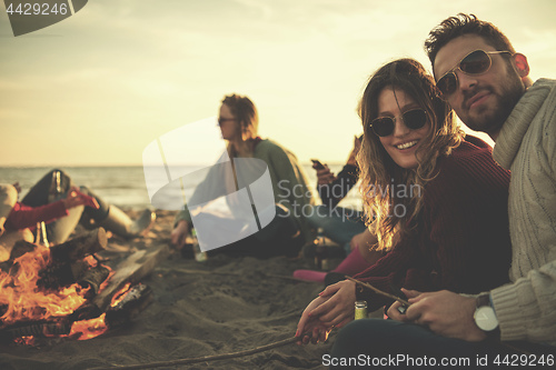 Image of Couple enjoying with friends at sunset on the beach