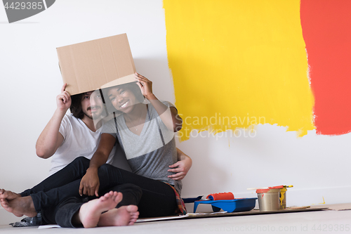 Image of young multiethnic couple playing with cardboard boxes