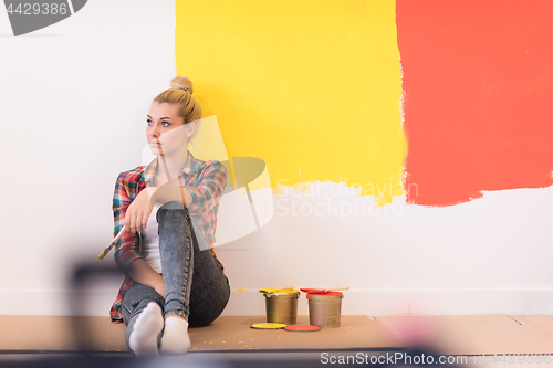 Image of young female painter sitting on floor