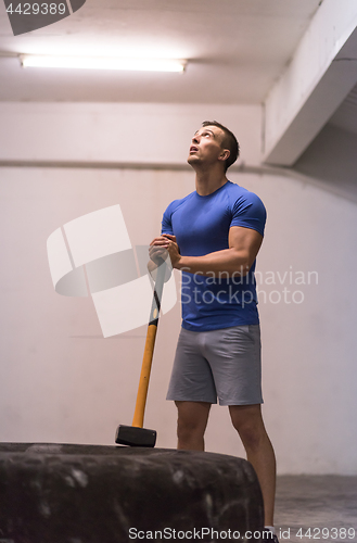 Image of man workout with hammer and tractor tire
