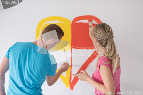 Image of couple are painting a heart on the wall