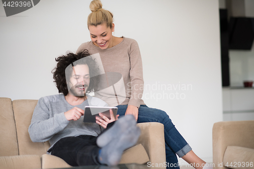 Image of couple relaxing at  home with tablet computers