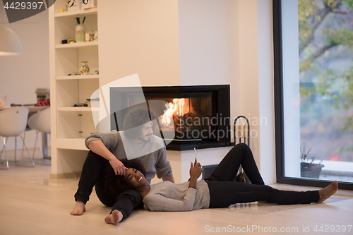 Image of multiethnic couple using tablet computer on the floor