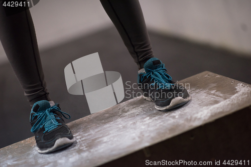 Image of black woman is performing box jumps at gym