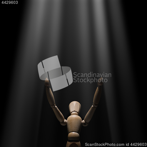 Image of Wooden mannequin raised hands to light