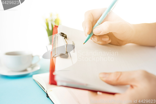 Image of The male hands holding pen. The trendy blue desk.