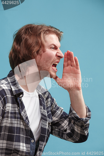 Image of Isolated on blue young casual man shouting at studio