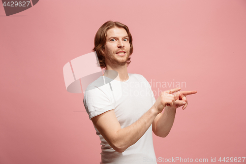 Image of Suspiciont. Doubtful pensive man with thoughtful expression making choice against pink background