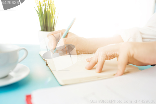 Image of The male hands holding pen. The trendy blue desk.