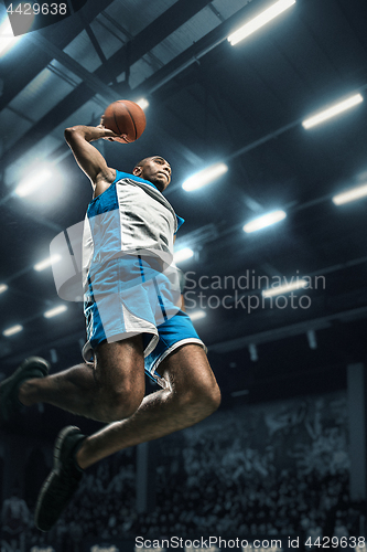 Image of Basketball player on big professional arena during the game. Basketball player making slam dunk.