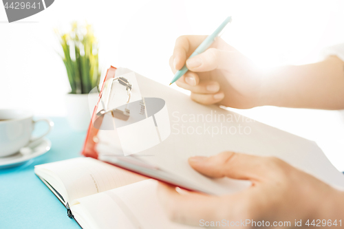 Image of The male hands holding pen. The trendy blue desk.