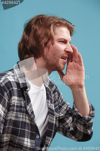 Image of Isolated on blue young casual man shouting at studio