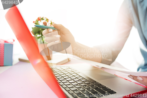 Image of Woman working on computer in office and holding glasses