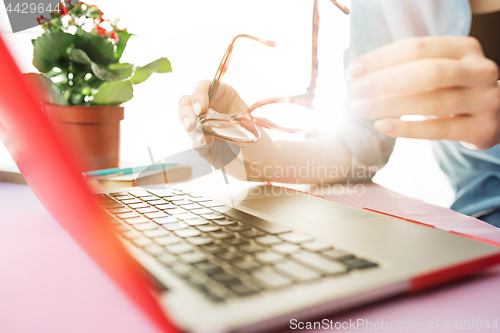 Image of Woman working on computer in office and holding glasses