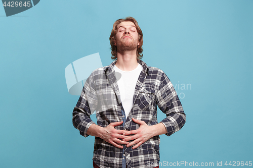 Image of The happy business man standing and smiling against blue background.