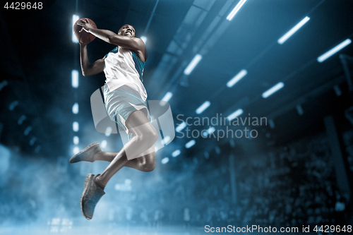 Image of Basketball player on big professional arena during the game. Basketball player making slam dunk.