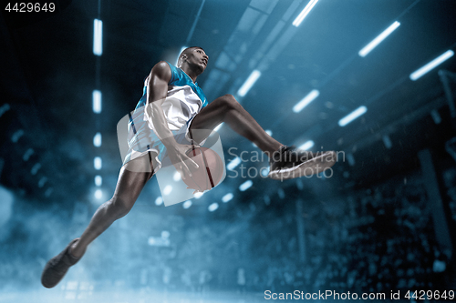 Image of Basketball player on big professional arena during the game. Basketball player making slam dunk.