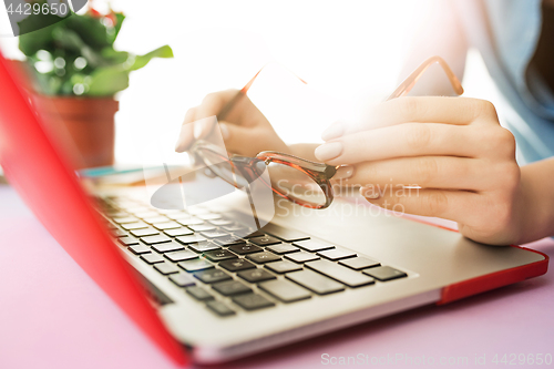 Image of Woman working on computer in office and holding glasses