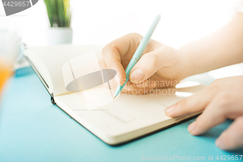 Image of The male hands holding pen. The trendy blue desk.