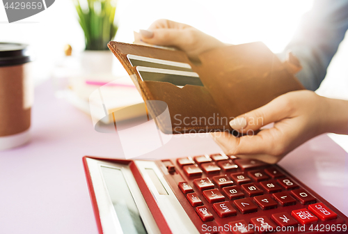 Image of woman is holding purse, credit card in hands and calculating the costs