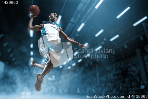 Image of Basketball player on big professional arena during the game. Basketball player making slam dunk.