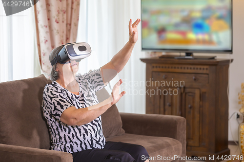 Image of Senior woman with virtual headset or 3d glasses playing