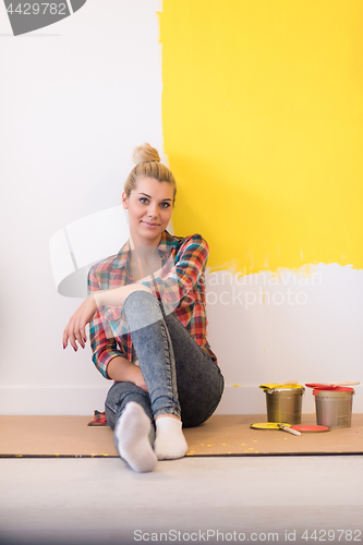 Image of young female painter sitting on floor