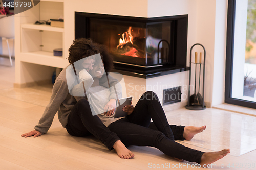 Image of multiethnic couple using tablet computer on the floor