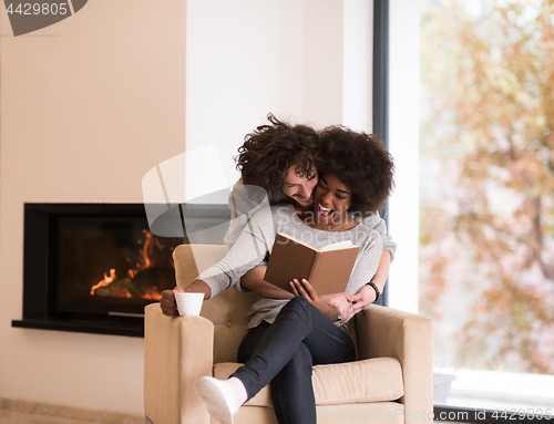 Image of multiethnic couple hugging in front of fireplace