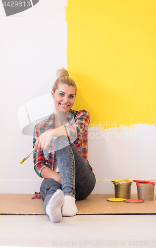 Image of young female painter sitting on floor