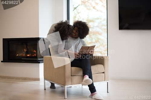 Image of multiethnic couple hugging in front of fireplace