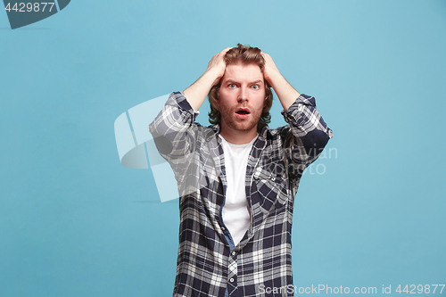 Image of Beautiful man looking suprised and bewildered isolated on blue