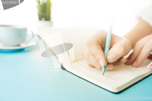 Image of The male hands holding pen. The trendy blue desk.