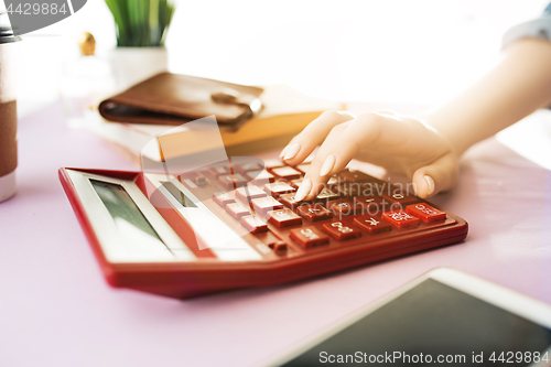 Image of woman is holding purse, credit card in hands and calculating the costs