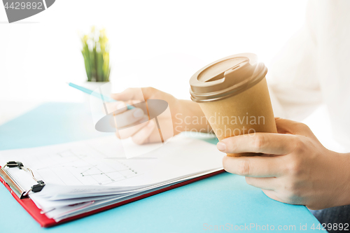 Image of The male hands holding pen and coffee. The trendy blue desk.