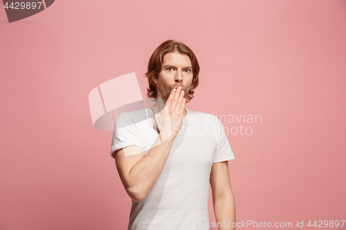 Image of The young man whispering a secret behind her hand over pink background