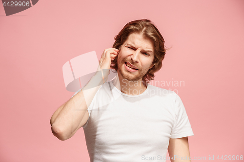 Image of The Ear ache. The sad man with headache or pain on a pink studio background.