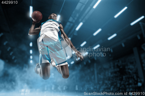 Image of Basketball player on big professional arena during the game. Basketball player making slam dunk.