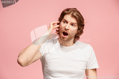 Image of The Ear ache. The sad man with headache or pain on a pink studio background.