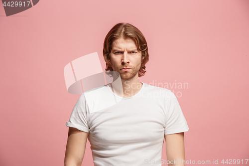 Image of The serious business man standing and looking at camera against pink background.