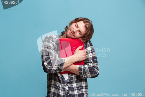 Image of Businessman hugging laptop on blue