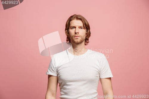 Image of The serious business man standing and looking at camera against pink background.