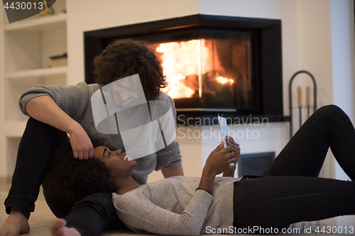 Image of multiethnic couple using tablet computer on the floor