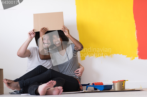 Image of young multiethnic couple playing with cardboard boxes