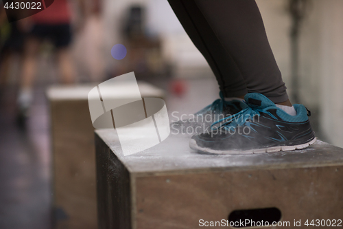 Image of black woman is performing box jumps at gym