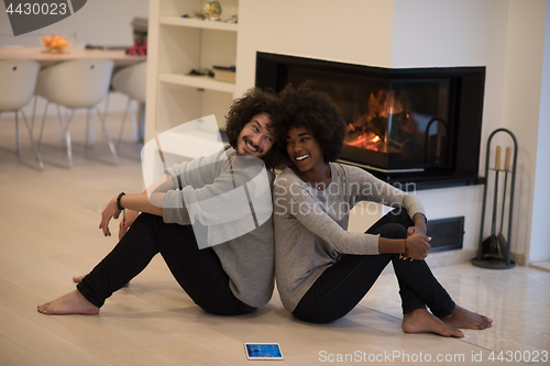 Image of multiethnic couple with tablet computer on the floor